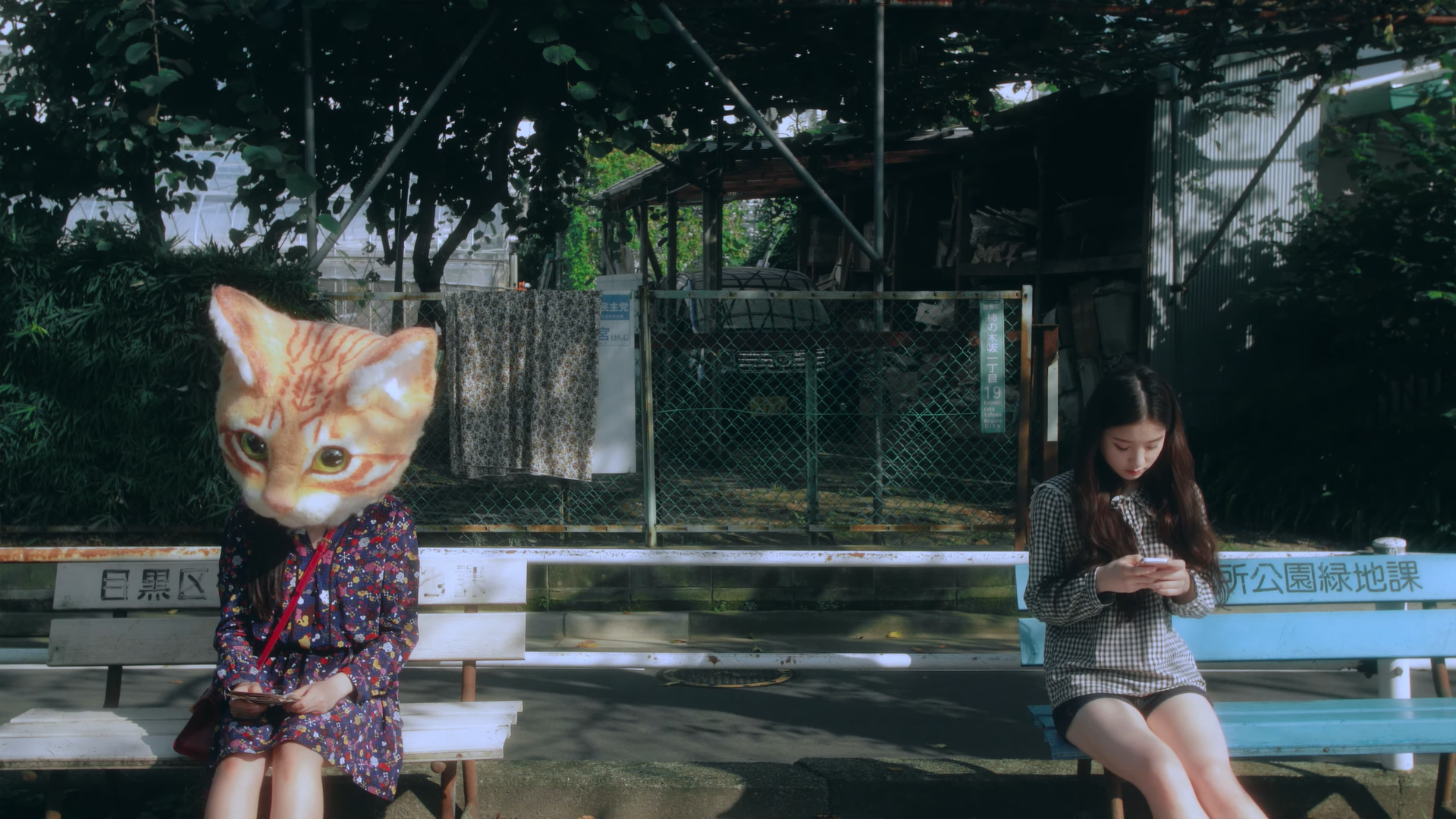 Hyunjin and Heejin sitting on benches. Heejin is looking at her phone.